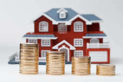 Início Miniaturas de casa no fundo, e na frente quatro pilhas de moedas em ordem crescente.